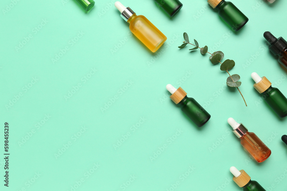 Bottles of cosmetic oil and eucalyptus branches on turquoise background