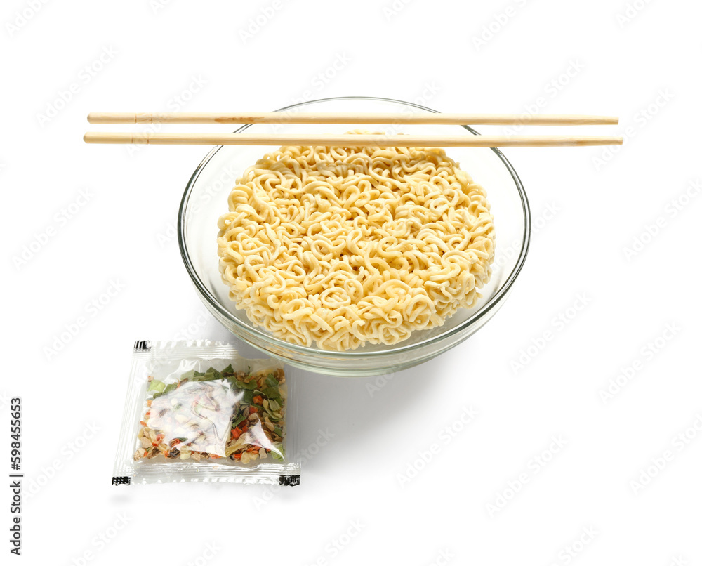 Raw instant noodles in bowl with wooden chopsticks and seasoning on white background