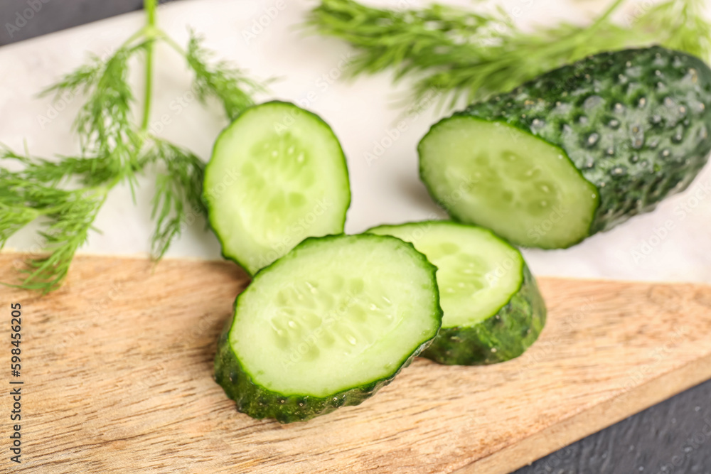 Board with fresh cut cucumber on table, closeup