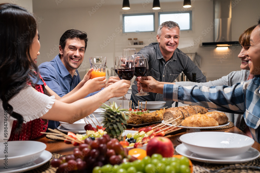 Multi-ethnic big family having dinner, enjoy evening party in house.