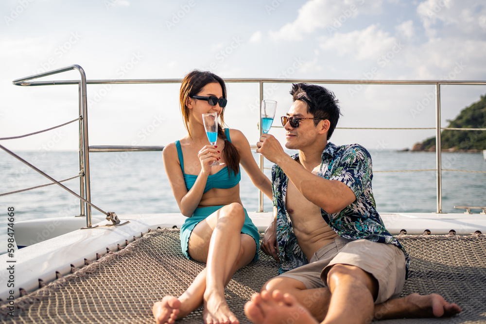 Asian beautiful couple drinking champagne while having party in yacht. 