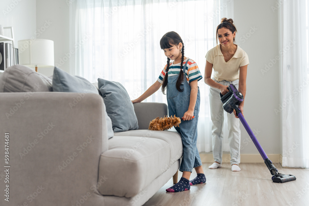 Caucasian beautiful mother cleaning house with young kid daughter. 