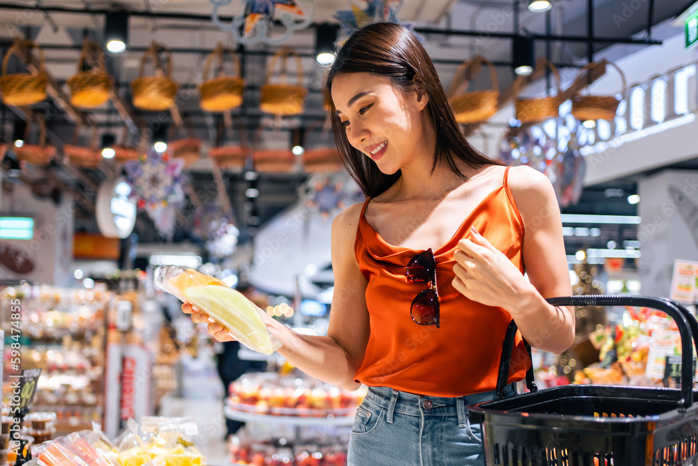 Asian young beautiful woman holding grocery basket walk in supermarket. 