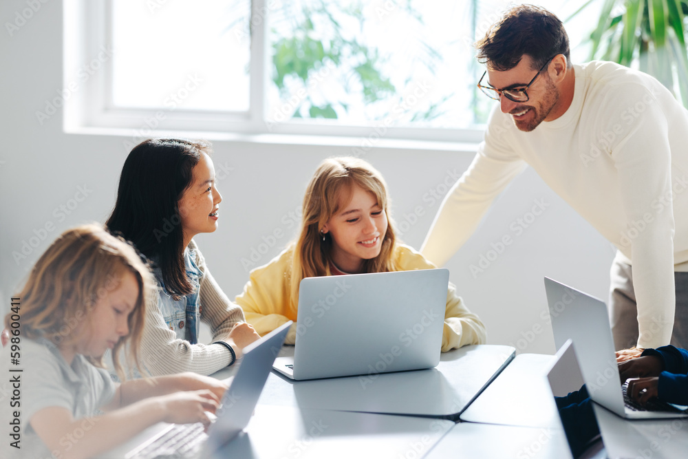 Computer-based learning in an elementary school: Teacher guiding a group of students in a coding cla