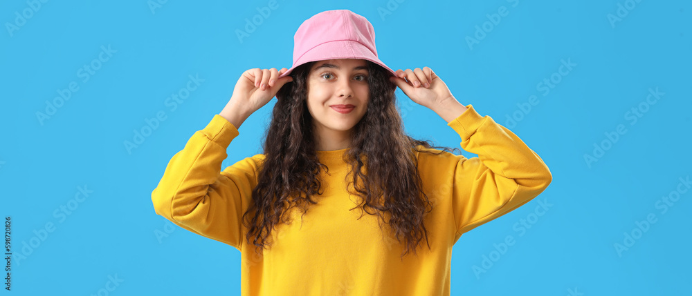 Teenage girl in pink bucket hat on blue background