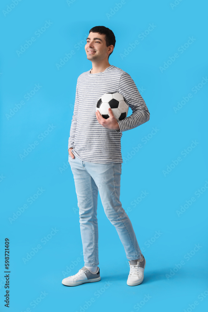 Young man with soccer ball on blue background