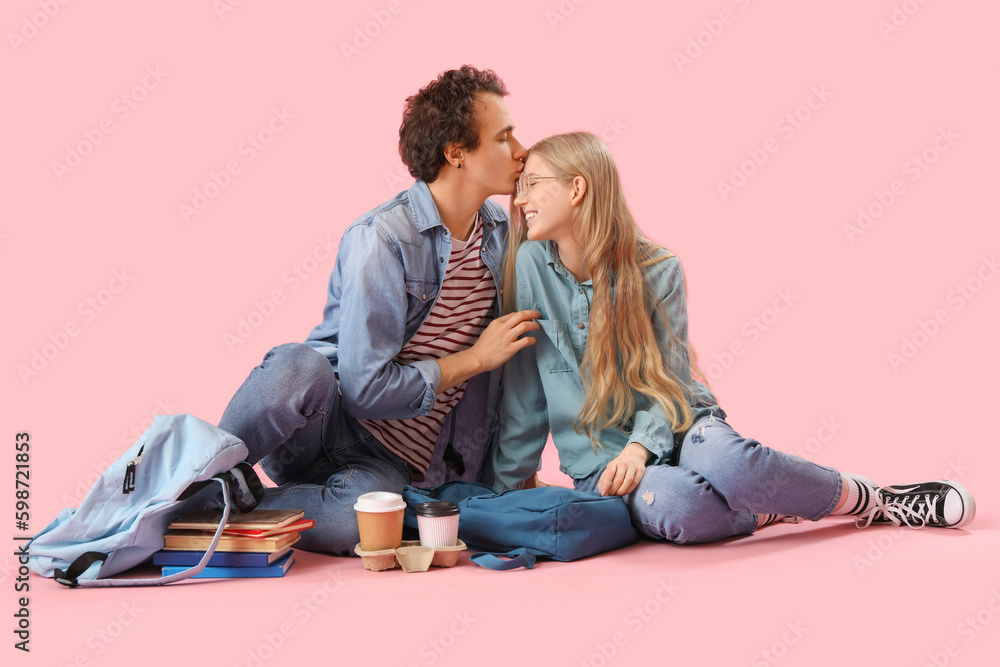 Teenage couple sitting on pink background