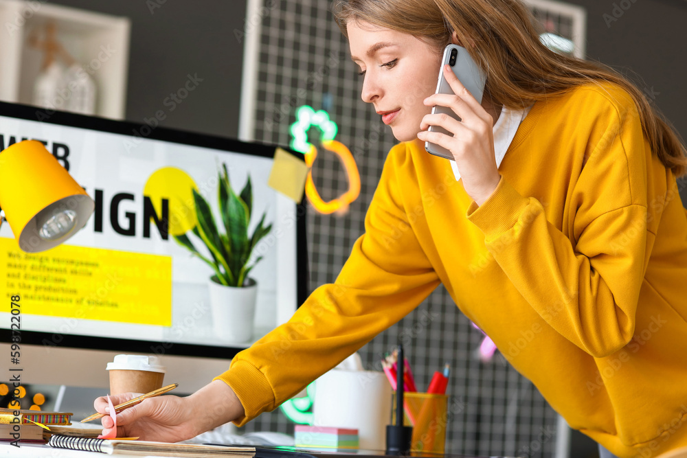 Female graphic designer talking by mobile phone in office