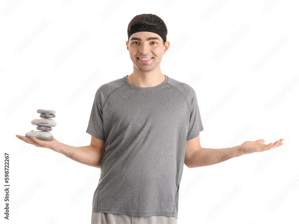 Sporty young man with spa stones on white background. Balance concept