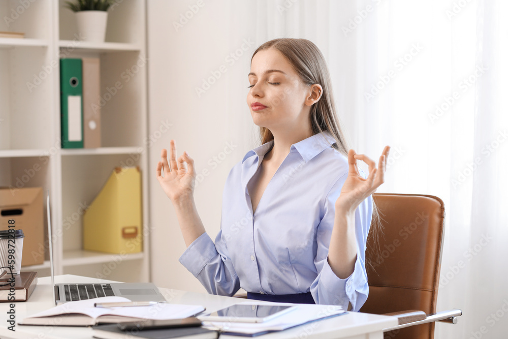 Young businesswoman meditating in office. Balance concept