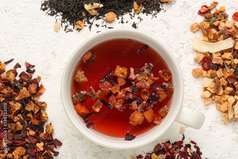 Composition with glass and heaps of dried fruit tea on white table