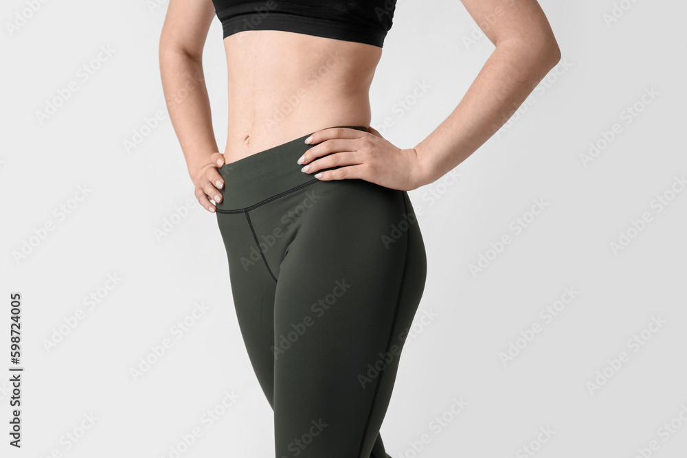 Sporty young woman in leggings on white background