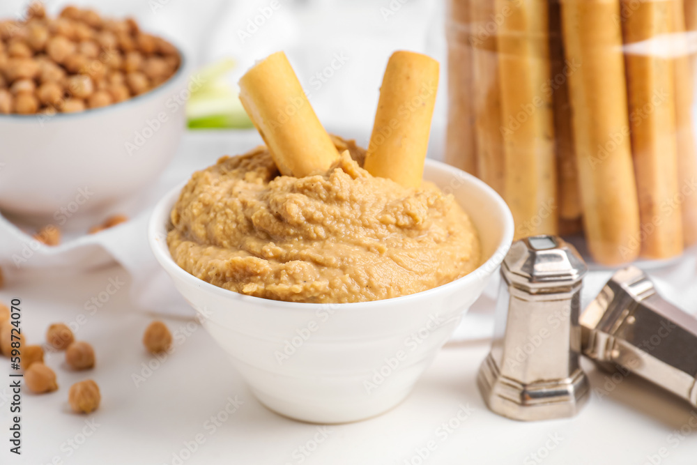 Bowl with tasty hummus and Italian Grissini on table