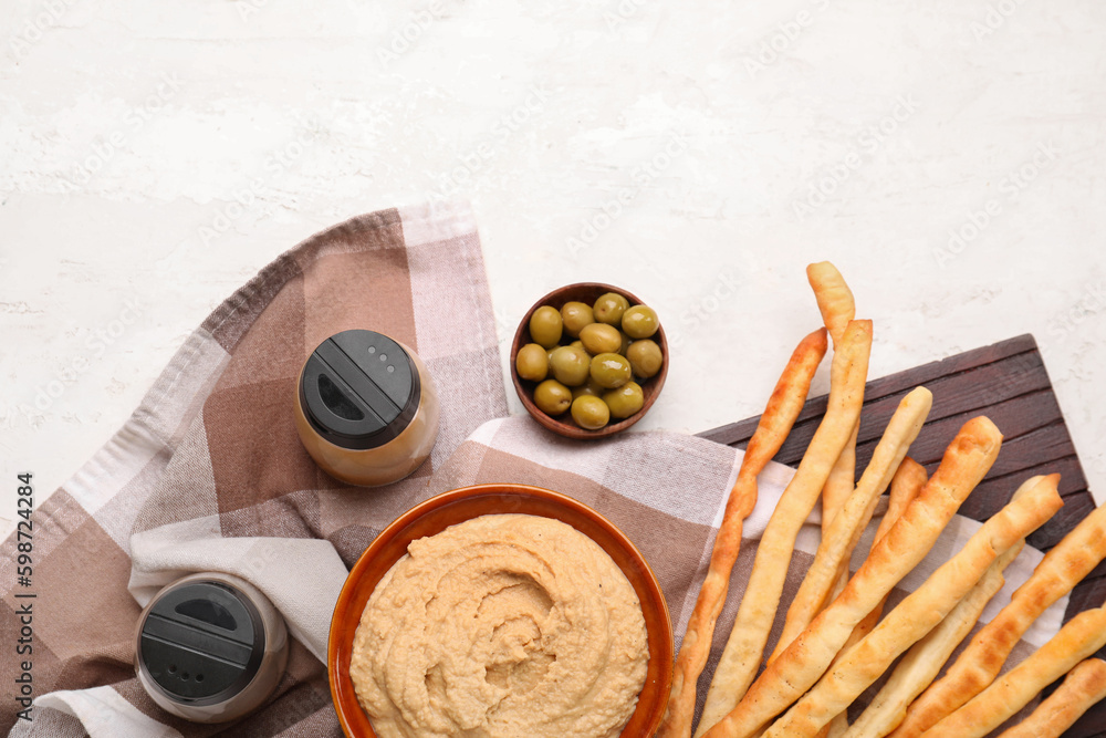 Bowl with tasty hummus and Italian Grissini on light background