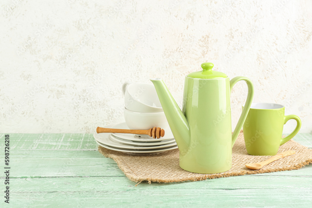 Wicker mat with stylish tea set on green wooden table