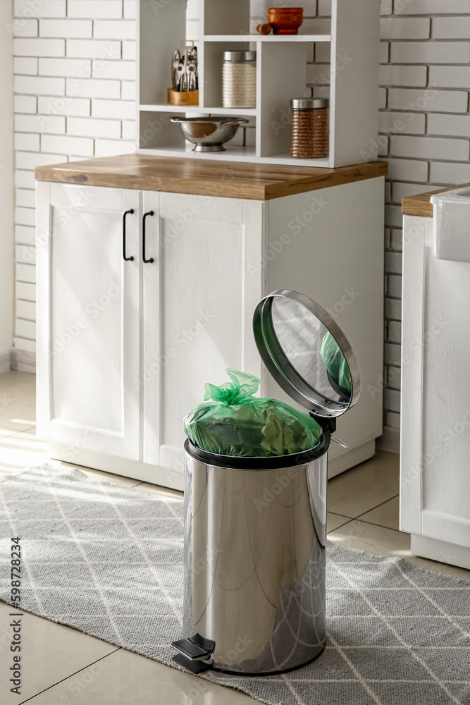 Full trash bin in interior of modern kitchen