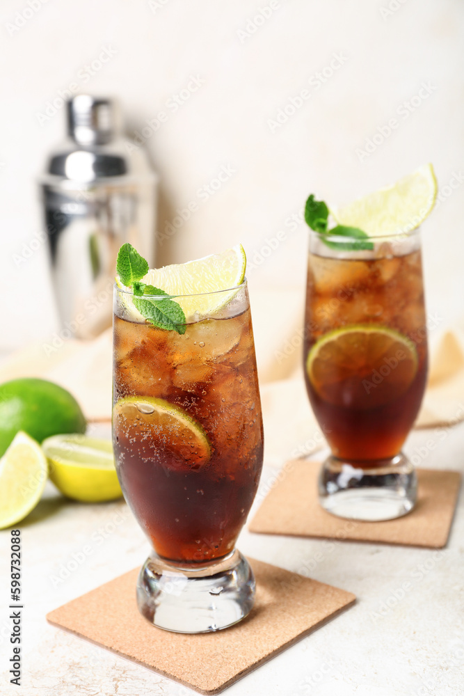 Glasses of cold Cuba Libre cocktail on light background