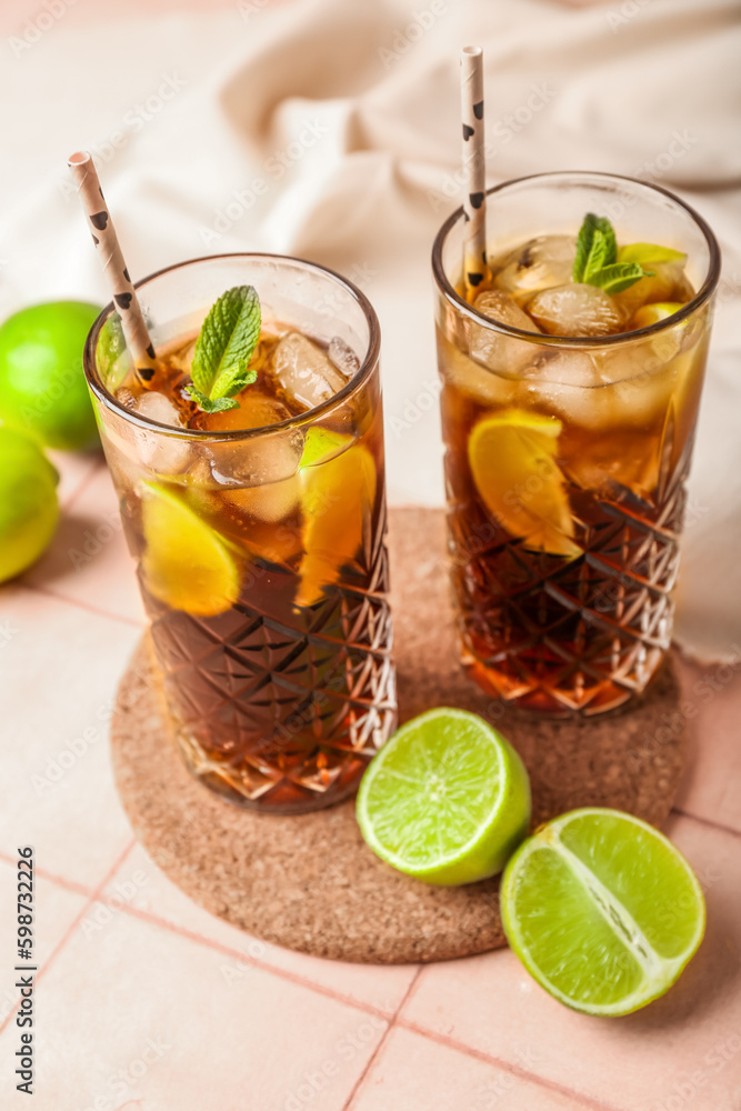 Glasses of cold Cuba Libre cocktail on light tile background