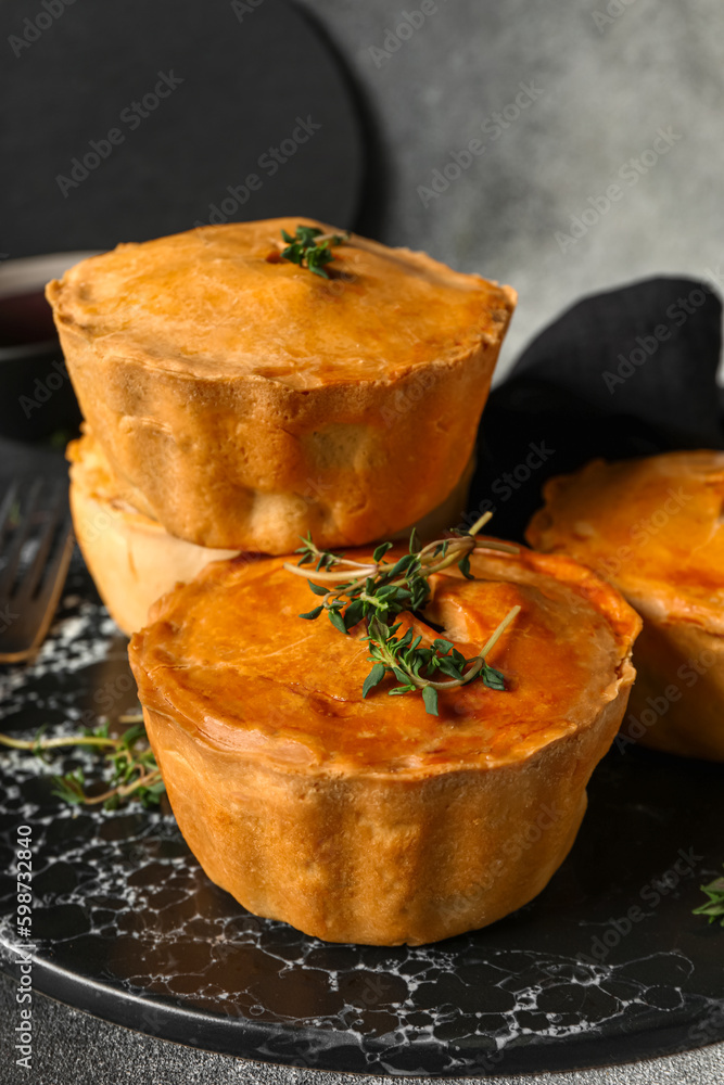 Slate board with tasty meat pot pies on light background