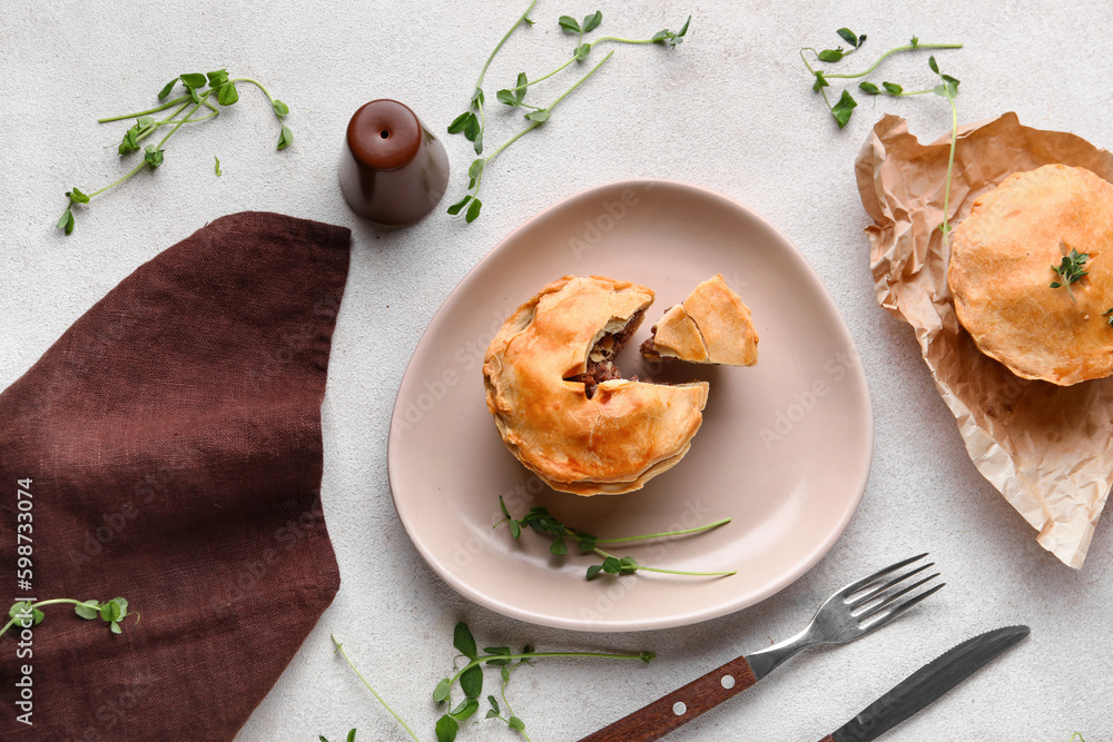 Plate with tasty meat pot pies on light background