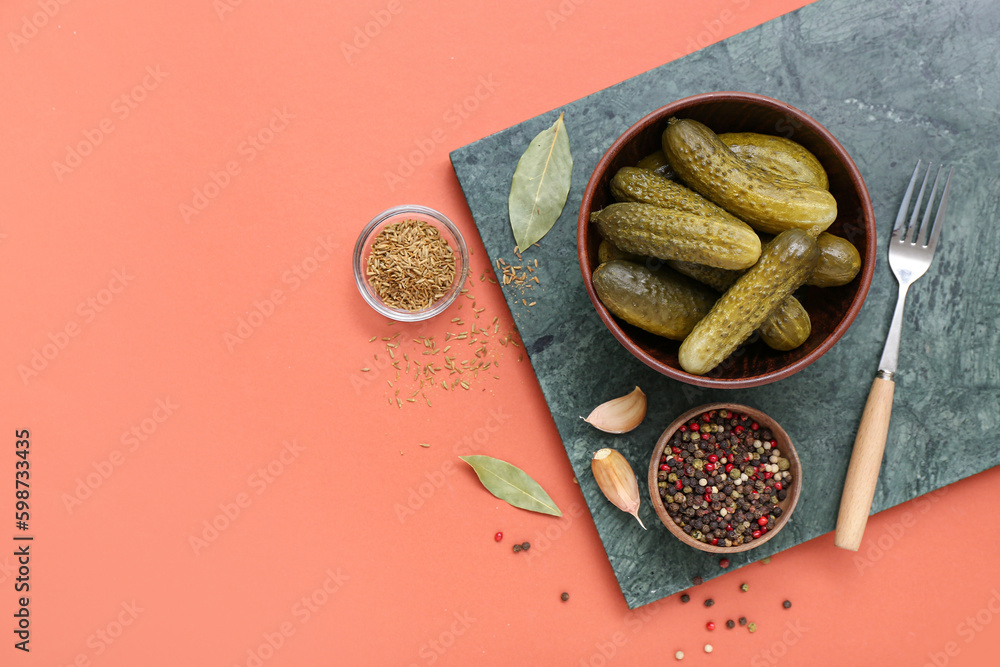 Board with bowl of tasty canned cucumbers and ingredients on red background