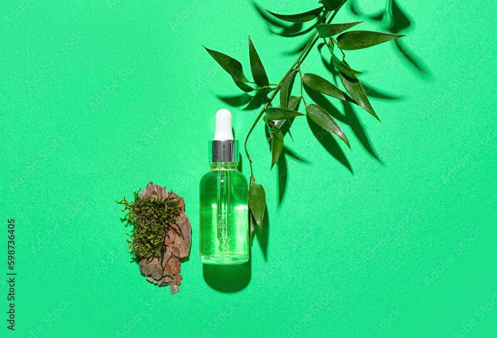 Bottle of cosmetic oil with eucalyptus twig, tree bark and moss on green background