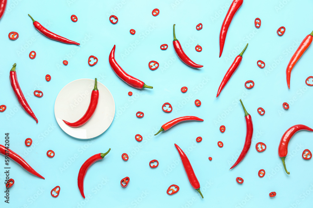 Plate with fresh chili peppers on blue background