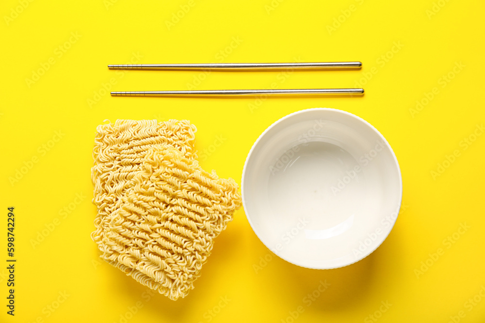 Raw instant noodles with empty bowl and chopsticks on yellow background