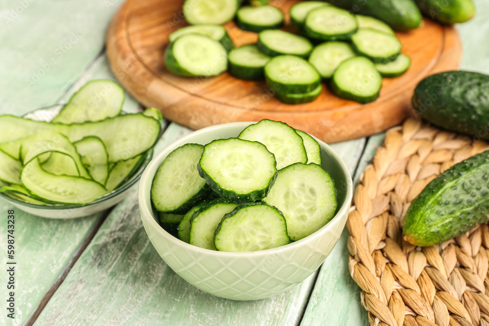 Bowl with pieces of fresh cucumber on light wooden background