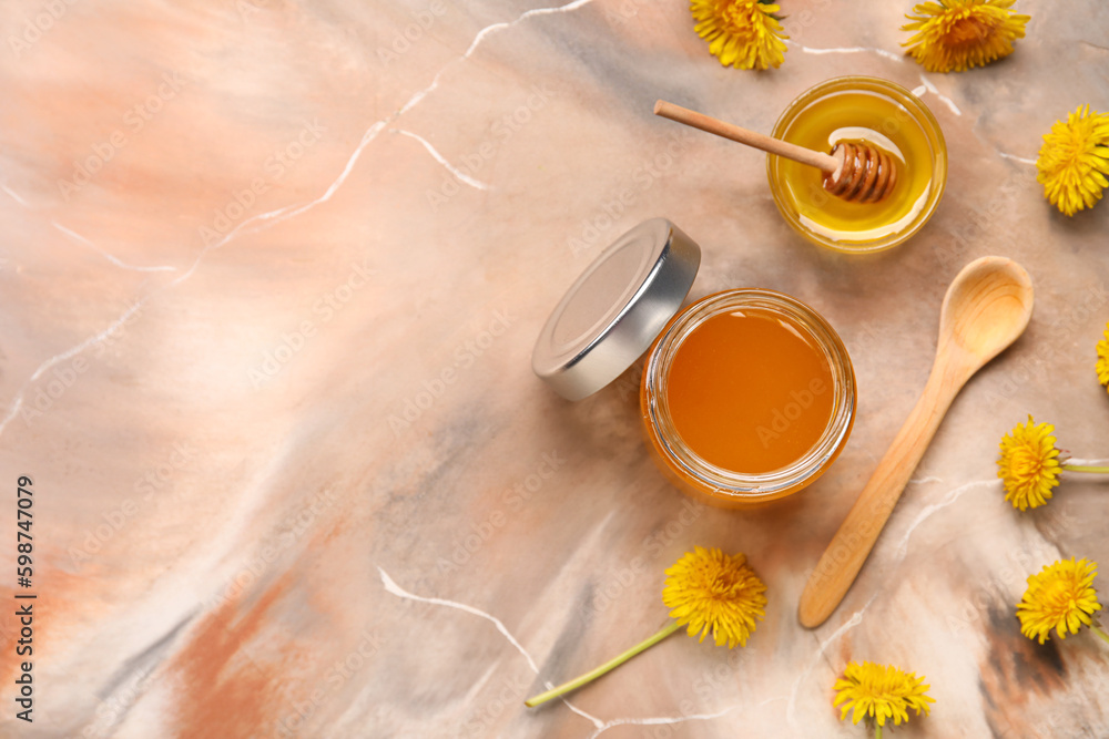 Jar and bowl with dandelion honey on marble background