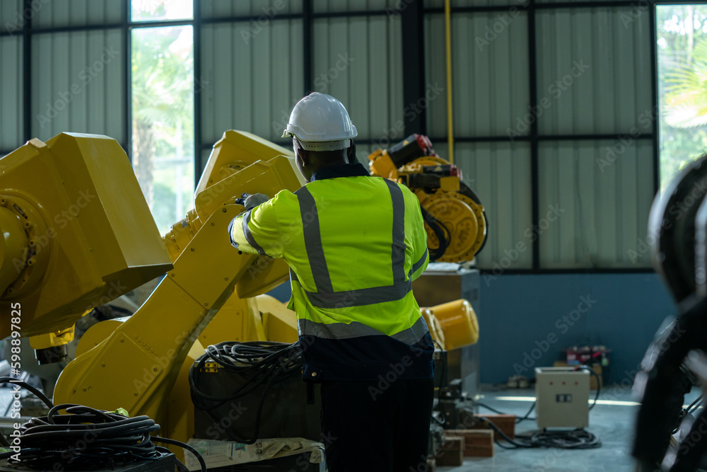 Engineer working with robot arm automated welding machine in modern metal factory.