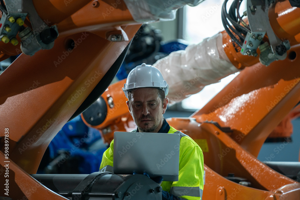 Engineer and mechanic worker checking and maintain industrial robot arm controller inside the factor