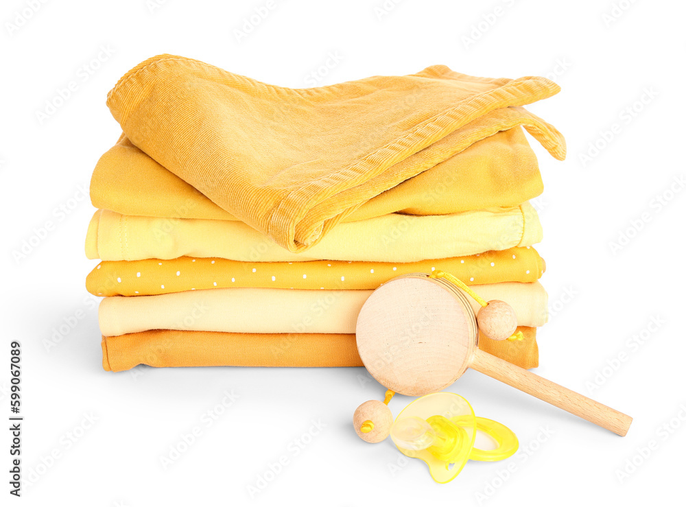 Stack of baby clothes, pacifier and wooden toy on white background