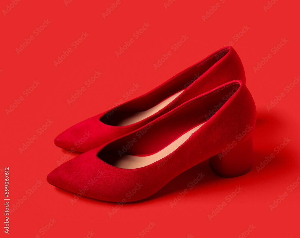 Pair of stylish female shoes on color background