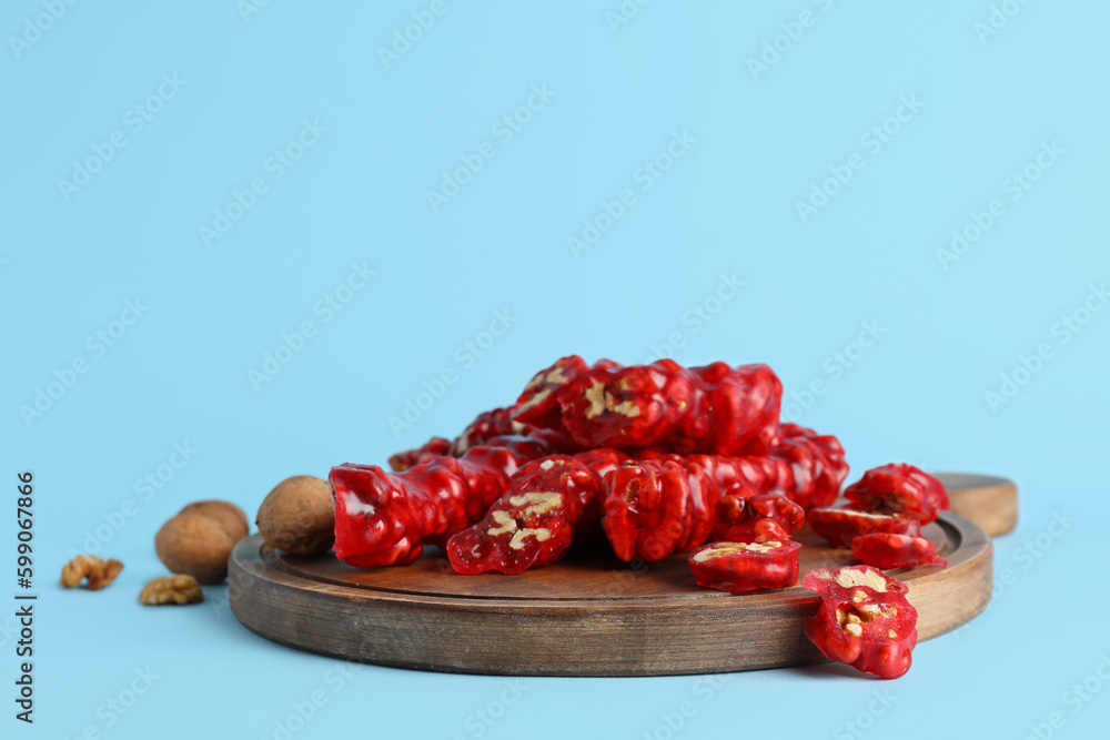 Wooden board with tasty churchkhela on color background