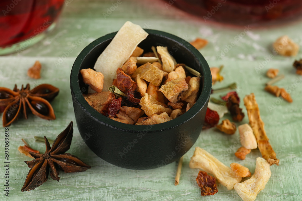 Bowl with dried fruit tea on green wooden table, closeup