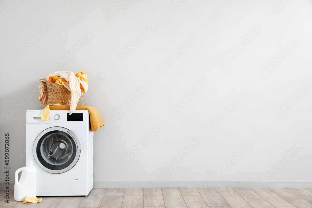 Basket with dirty clothes on washing machine in laundry room