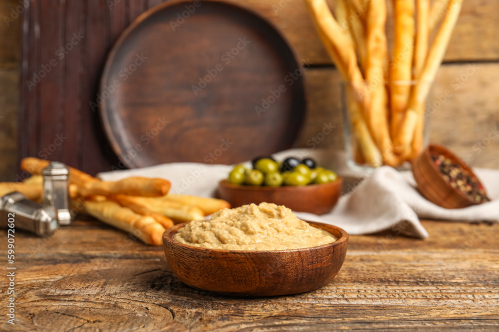 Bowl with tasty hummus on wooden background