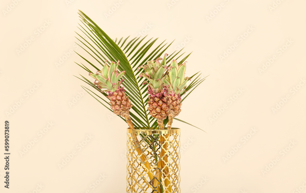 Vase with decorative pineapples and palm leaf on light background