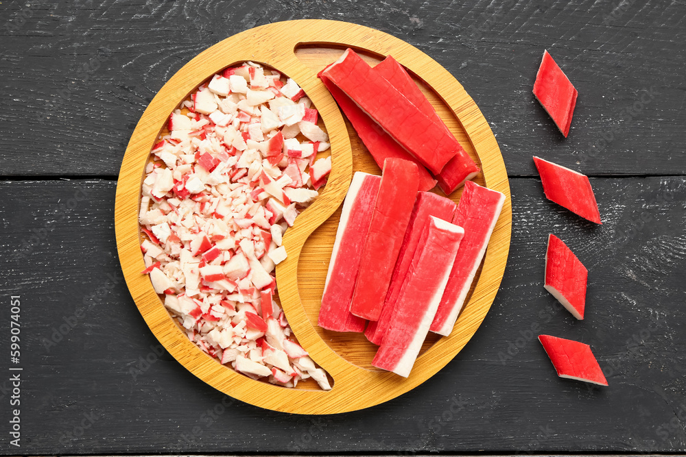 Plate with tasty crab sticks on dark wooden background