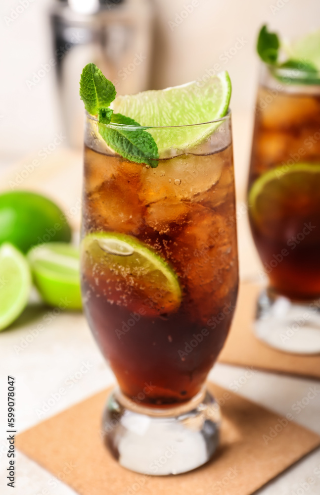 Glass of cold Cuba Libre cocktail on light background