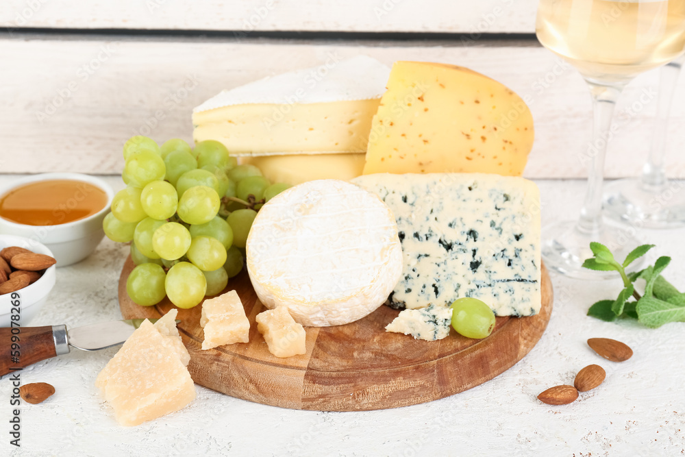 Wooden board with different types of cheese and grapes on table