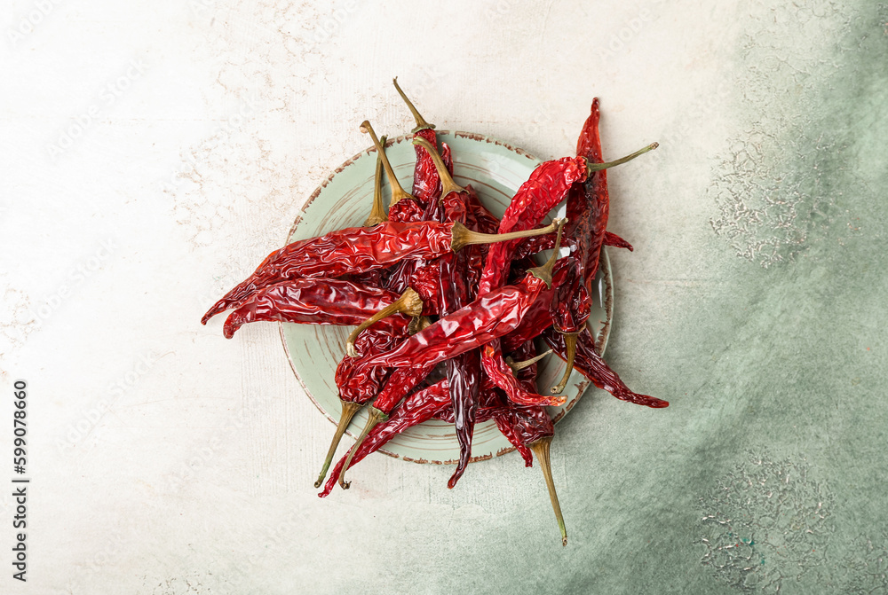 Plate with dry hot chili peppers on light background