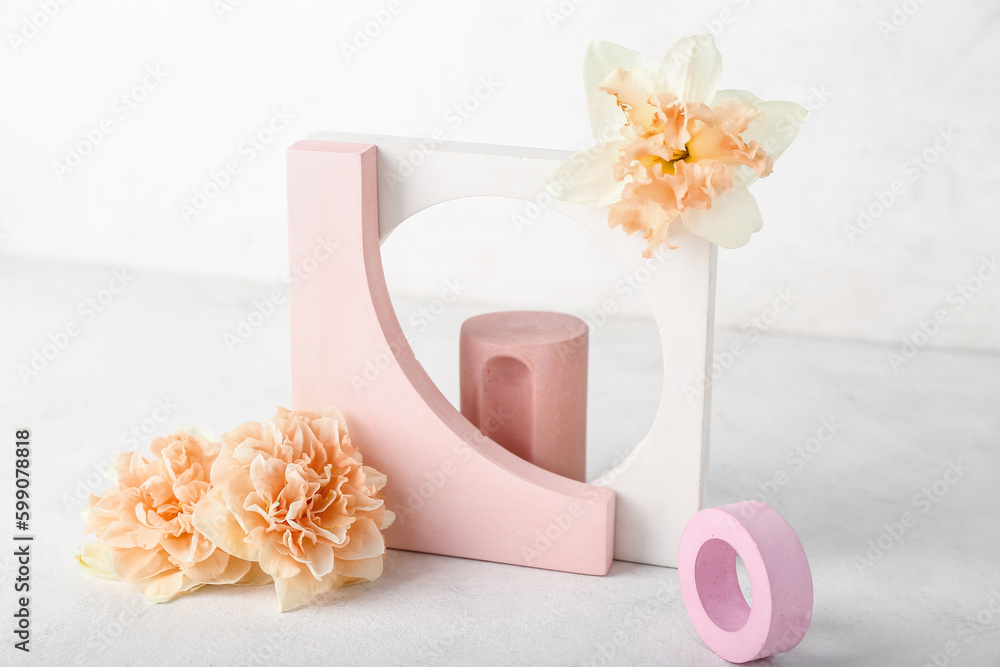 Decorative plaster podiums with daffodils on table against white wall