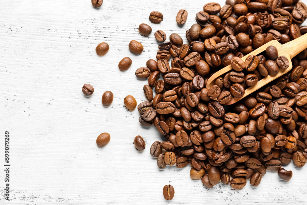 Scoop and coffee beans on light wooden background