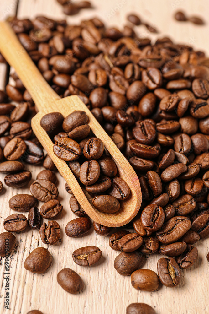 Scoop and coffee beans on light wooden background