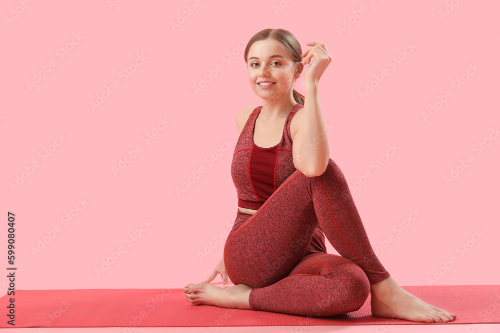 Sporty young woman doing yoga  on pink background