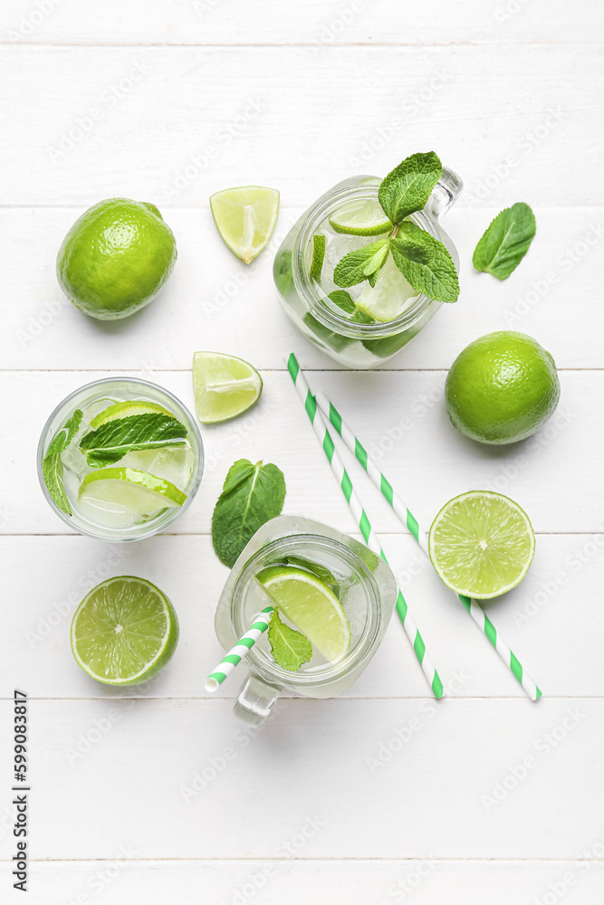 Mason jars and glass of tasty mojito with fresh fruits on light wooden background