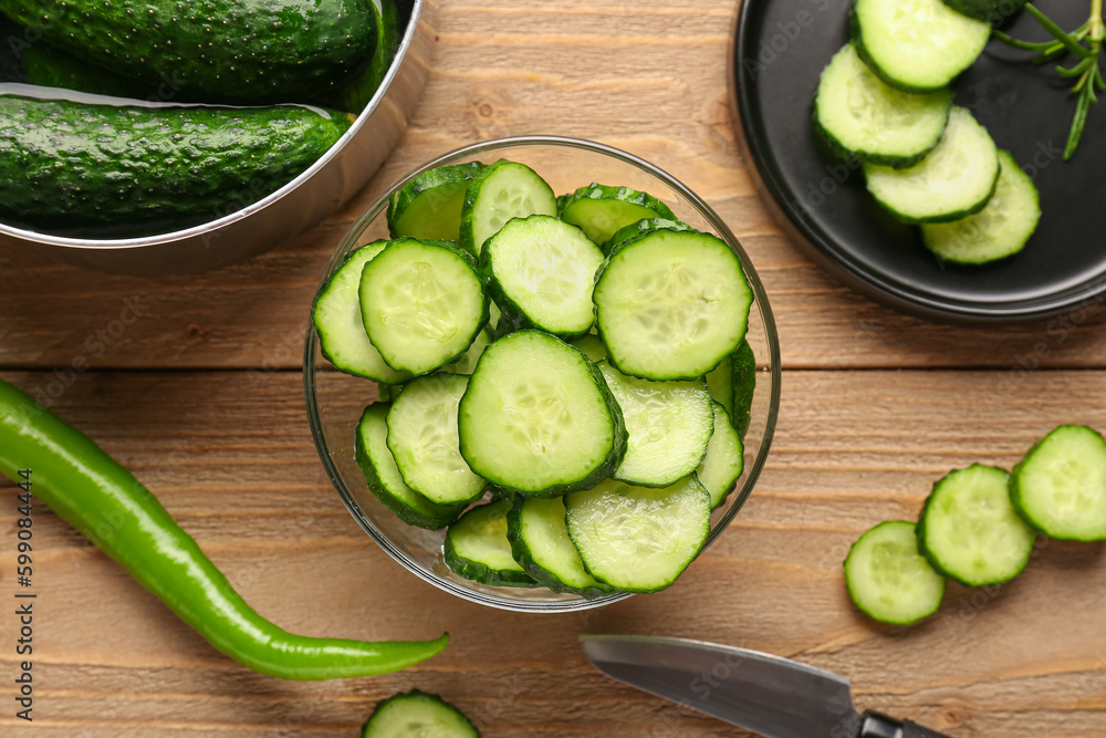 Bowl with pieces of fresh cucumber on wooden background