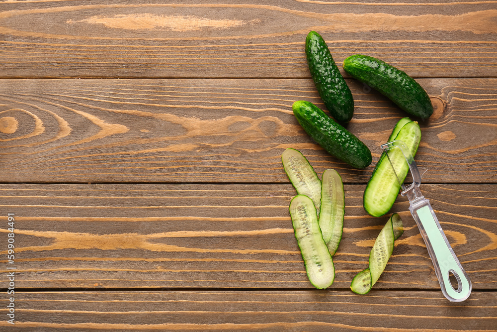 Fresh cucumbers and cut slices on wooden background